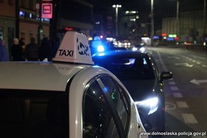 taksówka i radiowóz policyjny zaparkowane na ulicy