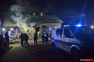 na ulicy przed budynkiem, w którym wybuchł pożar stoją ludzie, z prawej strony widoczny radiowóz policyjny, z lewej wóz strażacki