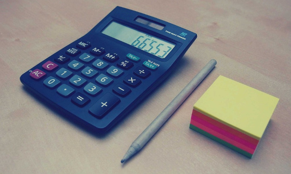 Kalkulator, długopis i kolorowe karteczki.