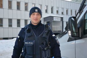 policjant stoi przed budynkiem komendy policji