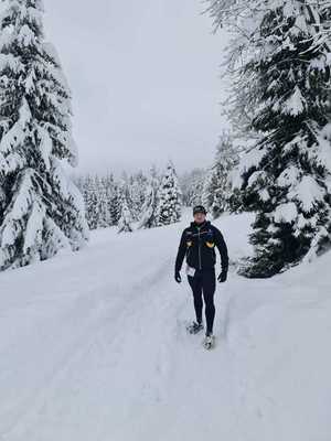 mł.asp. Paweł Molenda podczas biegu na drodze zasypanej śniegiem, wokół widać oprószone śniegiem drzewa