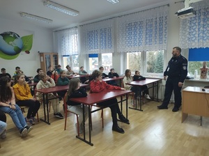 Policjant w szkolnej klasie rozmawia z dziećmi.