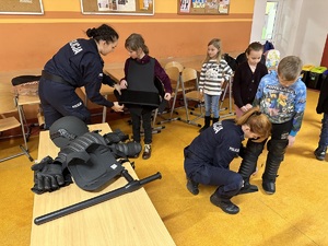 Policjantki zakładają dzieciom elementy stroju policyjnego.