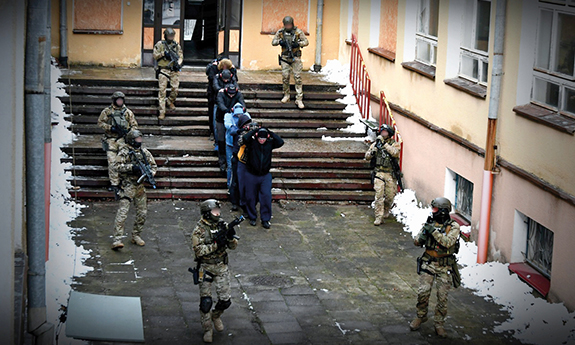 Policyjni kontrterroryści wyprowadzają ludzi z budynku.