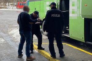 kierowca przed autobusem rozmawia z dwojgiem umundurowanych policjantów