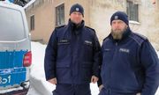 zdjęcie-dzień, zima, śnieg, policjanci dzielnicowi stoją obok radiowozu, w tle budynek