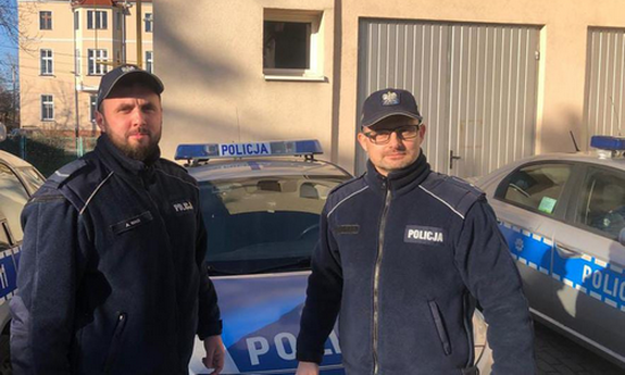 dwaj policjanci stoją przy radiowozie policyjnym