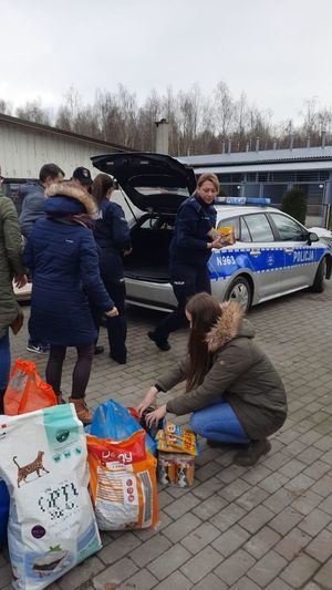policjanci i osoby cywilne pakują zebrane dary do radiowozu