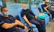 umundurowani policjanci siedzą w krwiobusie i oddają krew