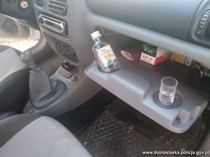 wnętrze samochodu, w schowku butelka i kieliszek