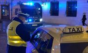 Umundurowany policjant kontroluje kierowcę taksówki w centrum Lublina. z tyłu widać policyjny radiowóz