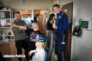 rodzina i umundurowany policjant w trakcie zwiedzania komendy