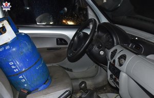 wnętrze samochodu, na miejscu pasażera stoi niebieska butla z gazem