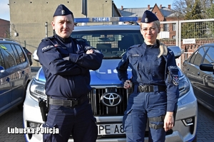 umundurowana policjantka i policjant stoją przy radiowozie