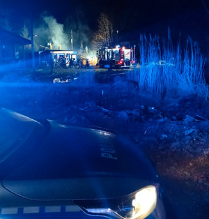 na miejscu zdarzenia widać płonący budynek, funkcjonariuszy i wóz straży pożarnej i policyjny radiowóz