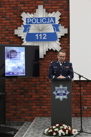 zastępca komendanta Głównego Policji przemawia stojąc przy mównicy, w tle na ścianie gwiazda policyjna