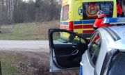 radiowóz policyjny z otwartymi drzwiami od strony kierowcy stoi tuż za żółtą karetką pogotowia przy której stoi medyk w pomarańczowym kombinezonie