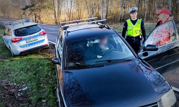 Policjant ruchu drogowego i medycy przy poszkodowanym kierującym