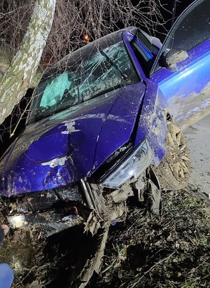 Rozbity, niebieski samochód marki Audi, który uderzył w drzewo