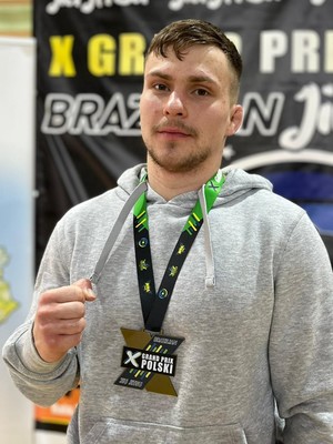 Sierżant Karol Lisiecki w stroju sportowym prezentuje medal