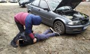 Zatrzymana osoba podejrzana o kradzież samochodu lezy na ziemi, a nad nią kuca policjant