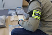 policjant kuca, przy nim widać rozłożone zabezpieczone środki odurzające znajdujące się w woreczkach