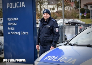 Umundurowany policjant stojący przy radiowozie