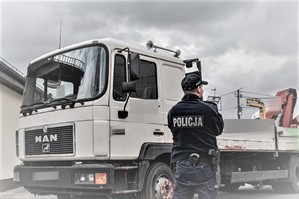 samochód ciężarowy, który brał udział w kolizji i stojący przy nim policjant
