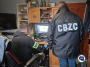 dwaj policjanci Centralnego Biura Zwalczania Cyberprzestępczości przed komputerem. Jeden stoi, drugi siedzi