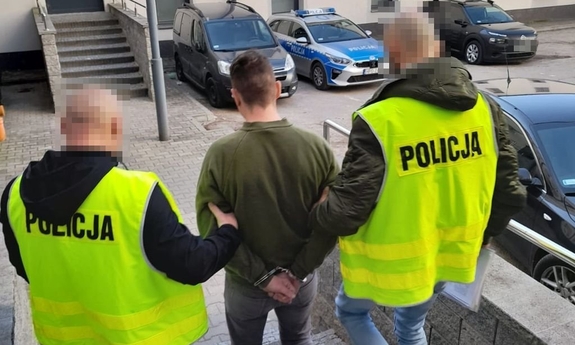 policjanci prowadzą zatrzymanego mężczyznę