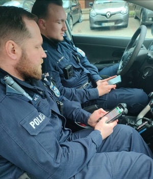 policjanci siedzą w radiowozie i korzystają z e-notatników