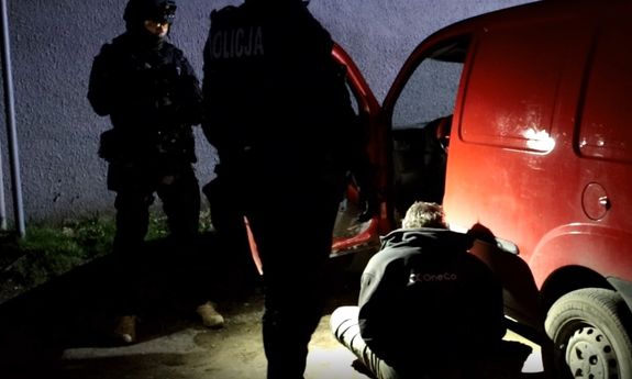 zatrzymany siedzi na ziemi przy samochodzie, który ma otwarte drzwi od strony kierowcy, przy nim stoją dwaj umundurowani policjanci z grupy realizacyjnej Komendy Miejskiej Policji w Poznaniu