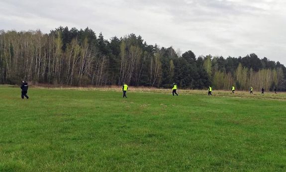 Umundurowani funkcjonariusze stojący na polu