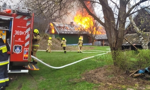 Pożar drewnianego domu i strażacy podczas akcji gaśniczej