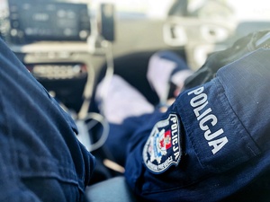 zbliżenie na rękaw z naszywką policjanta siedzącego w radiowozie
