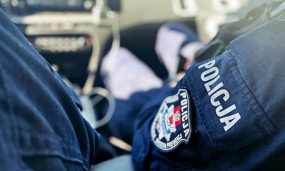 zbliżenie na rękaw z naszywką policjanta siedzącego w radiowozie