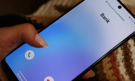 dłoń trzymająca telefon, na wyświetlaczu połączenie przychodzące z banku