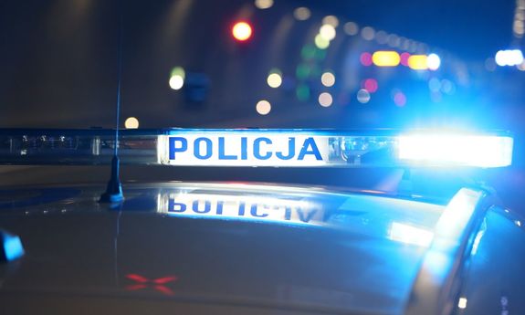 Zdjęcie przedstawia fragment dachu radiowozu z włączonymi sygnałami świetlnymi.