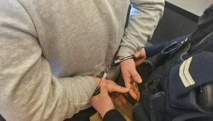 policjant zakłada zatrzymanemu kajdanki
