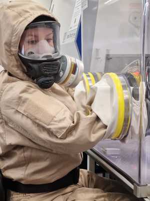 kobieta w specjalnym kombinezonie z zabezpieczonym materiałem w mobilnym laboratorium ZEUS-2