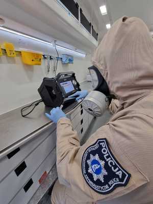 kobieta w specjalnym kombinezonie z zabezpieczonym materiałem w mobilnym laboratorium ZEUS-2