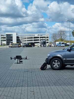 dron stoi przed plecakiem opartym o auto