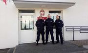 trzech umundurowanych policjantów stoi przy drzwiach wejściowcyh do posterunku policji