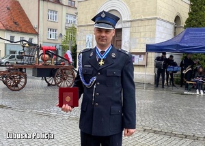 umundurowany policjant z odebraną odznaką Krzyża Rycerskiego Świętego Floriana