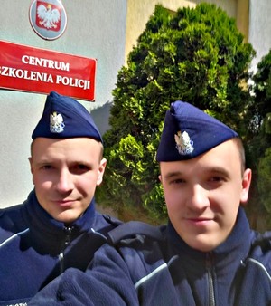 Dwaj policjanci w furażerkach na tle napisu Centrum Szkolenia Policji w Legionowie