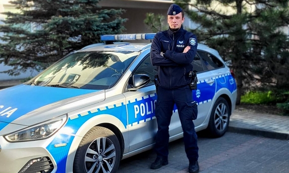 umundurowany policjant stoi przy radiowozie