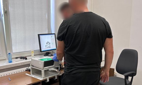 Zdjęcie przedstawia zatrzymanego podczas pobierania odcisków palców
