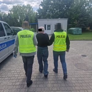 dwa policjanci prowadzą zatrzymanego