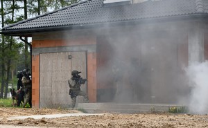 kontrterroryści widoczni przy budynku w chmurze dymu