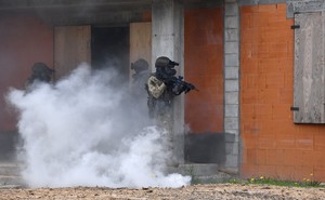 kontrterroryści widoczni przy budynku w chmurze dymu
